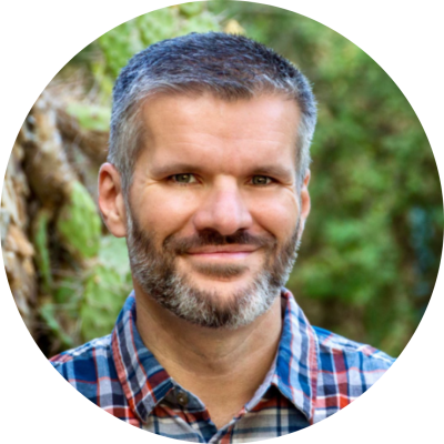 A man with short, salt-and-pepper hair and a beard wearing a plaid shirt